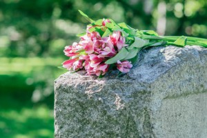 Rosa Blumen auf einem hellen Grabstein Tod der Eltern und Trauer