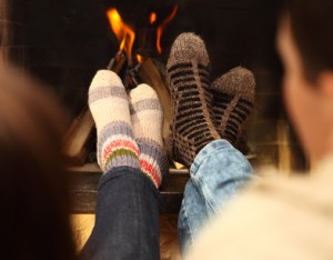 Nahaufnahme von Beinen eines Paars mit dicken Socken vor einem Kamin